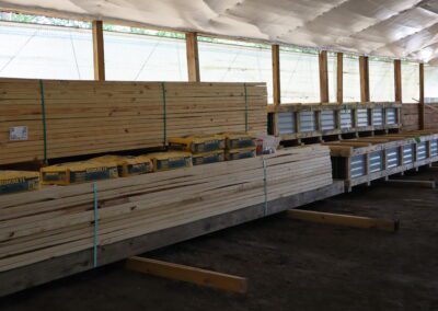 Stacks of treated lumber in a warehouse with labels indicating sizes.
