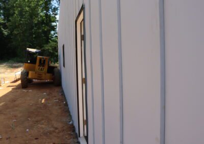 Side view of a construction site with a yellow bulldozer next to a building.