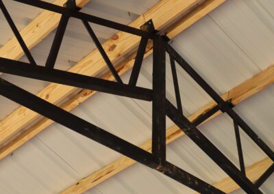 Interior of an empty metal barn with wooden framing and dirt floor.