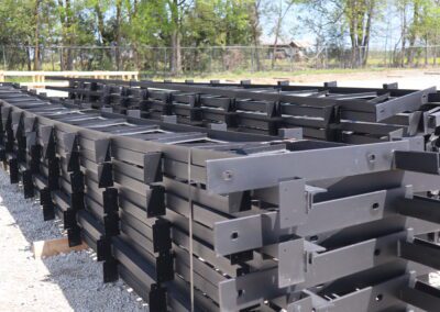 Rows of stacked black metal beams in an outdoor storage yard.